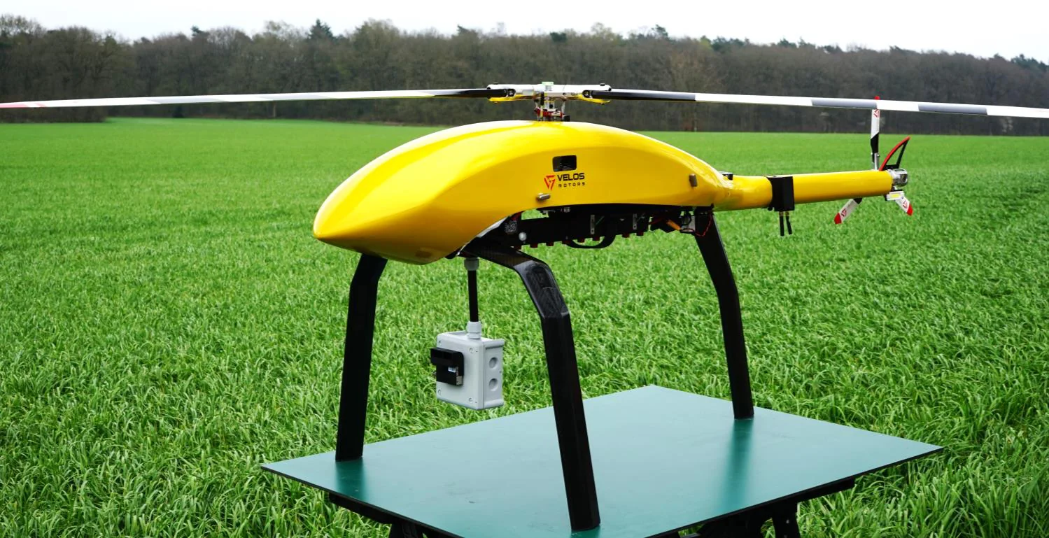 Yellow helicopter-type drone on grass with a sensor payload mounted underneath